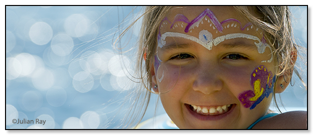 A young girl with a painted face smiles